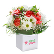 There's a delightful sense of joy and care woven into this full, vibrant bouquet-a true reflection of Bexley's welcoming spirit and close-knit community. Nestled upright in a snowy white gift bag, the arrangement brings together lush coral and red carnations-their ruffled petals soft and inviting with a gentle, sweet aroma-as well as clear white daisies, each highlighted by a zesty yellow-green center that seems to beam with happiness. Wisps of white baby's breath scatter between the blooms, adding an element of lightness and softness, like drifting clouds over Bexley's village lanes. Deep green, glossy leaves form an abundant base, elegantly framing the bouquet to create a rounded, harmonious shape reminiscent of handcrafted displays at local farmers' markets. Peeking from within, a few unopened buds tinged with purple and rose hint at new beginnings, echoing the quiet promise of spring after a walk in Foots Cray Meadows. The entire composition radiates freshness and sincerity, making it the perfect surprise for a birthday gathering, celebratory event, or just as a thoughtful pick-me-up for a loved one in Bexleyheath or Albany Park. The carefully tied handles and impeccable presentation suggest a bouquet ready to bring a smile, fill a room with colour, and make a lasting impression-expertly arranged by a Bexley florist who knows how to express emotion through flowers, every time.